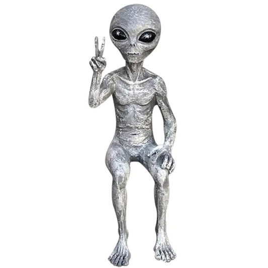 Silver alien figurine making a peace sign on a white background