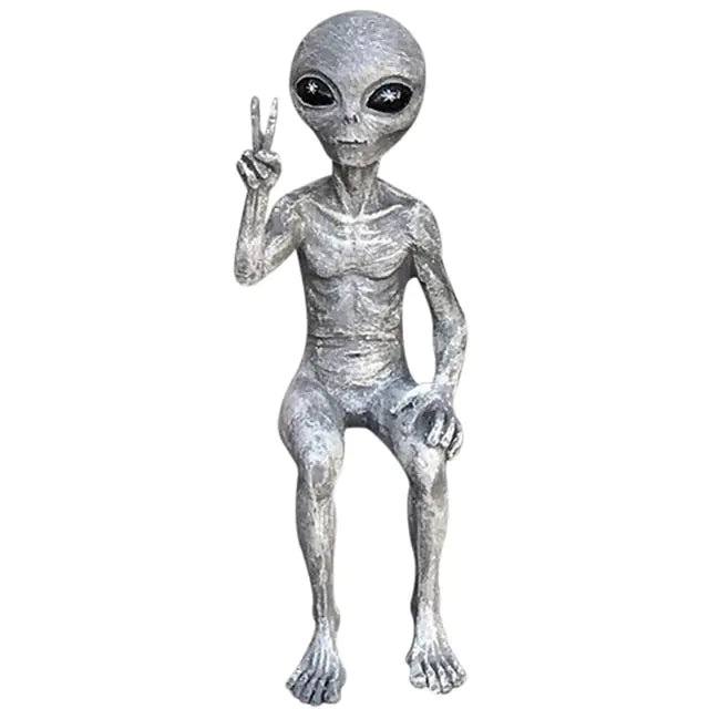 Silver alien figurine making a peace sign on a white background